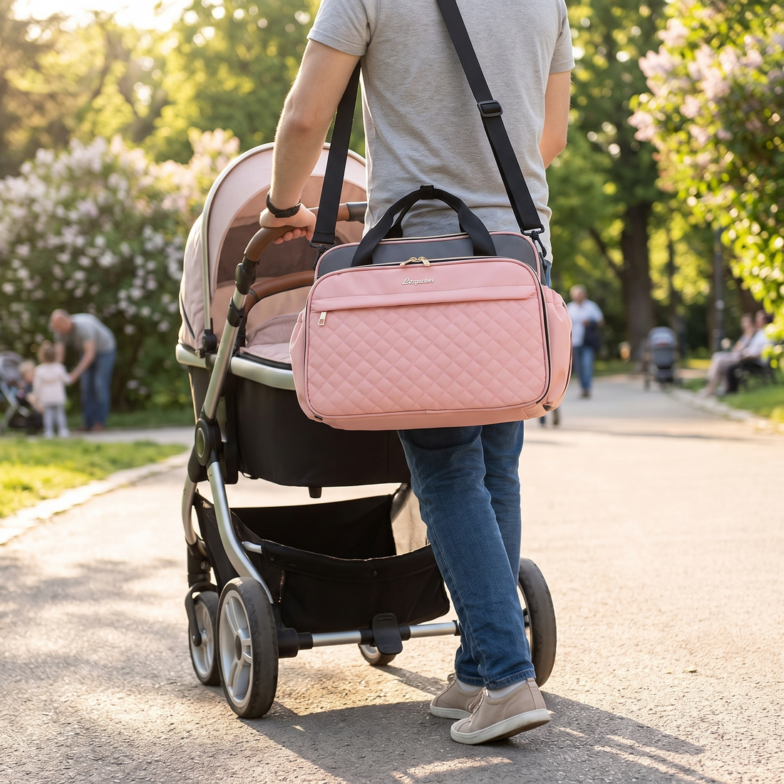 Crossbody Diaper Bag with 18 Pockets, hanging on a stroller pushed by a parent in a park
